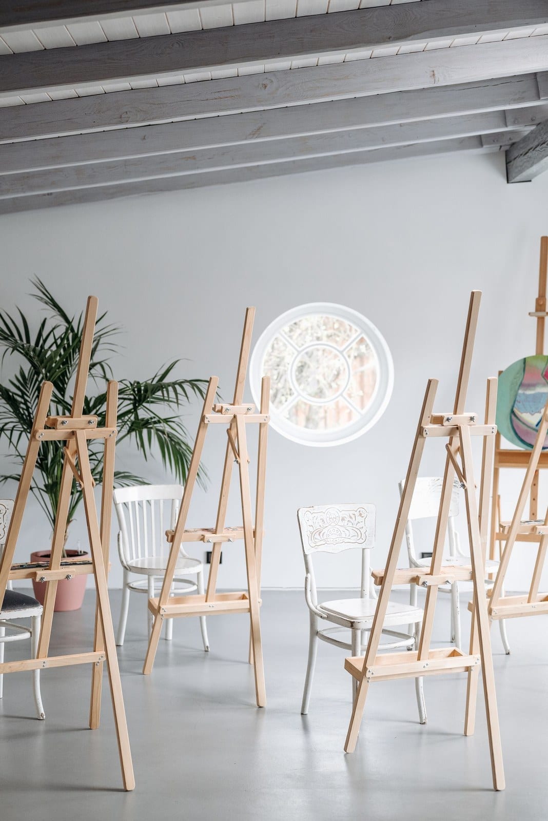Sala do atelier com cavaletes de madeira e cadeiras brancas, prontos para uma sessão