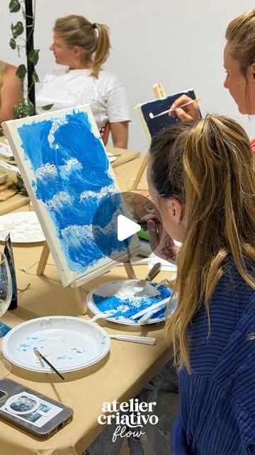 Participantes a pintar telas em tons de azul, à volta da mesa do atelier