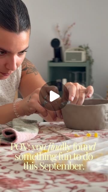 Mãos a moldar uma taça de barro sobre uma mesa de trabalho